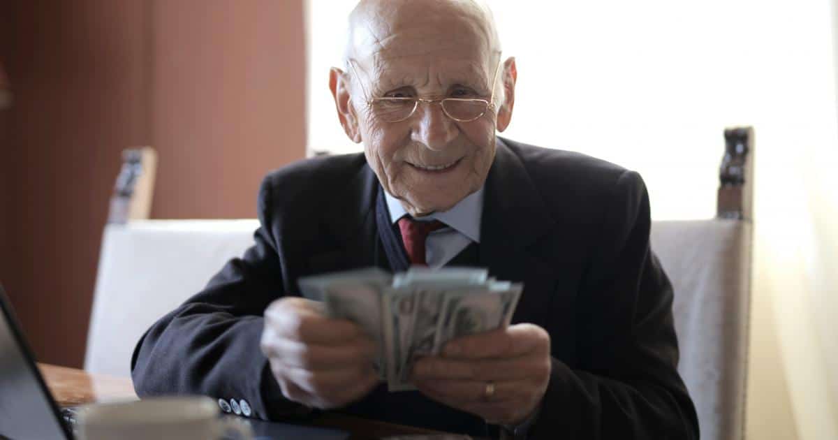 happy-senior-businessman-counting-money-while-sitting-at-3823540.jpg