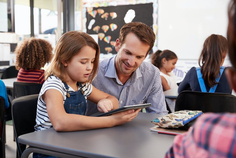 Enseignant et fille regardant la tablette informatique.